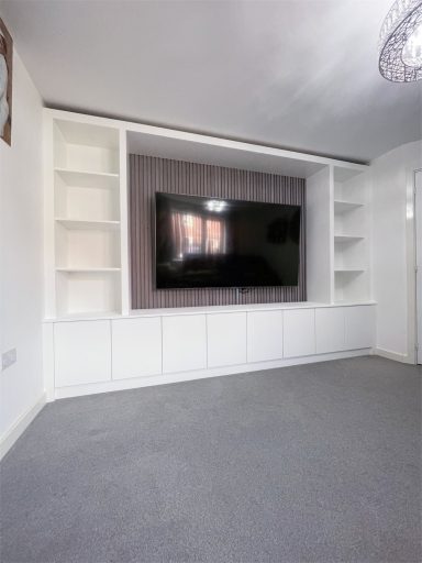 Modern living room featuring a wall-mounted TV and built-in white shelving.